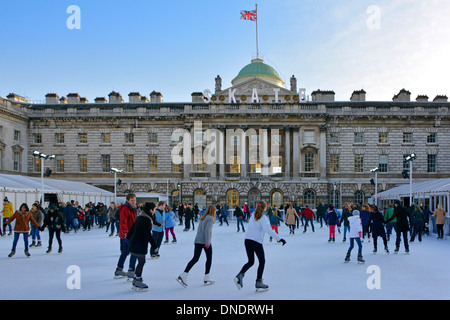 Adulti e bambini pattinatori di ghiaccio con sfondo storico Somerset House Edificio e cortile sulla temporanea pista di pattinaggio invernale Strand Londra Inghilterra Regno Unito Foto Stock