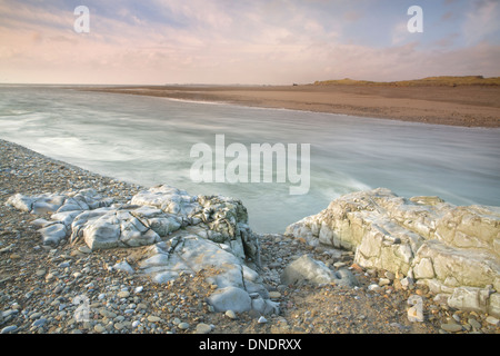 Il fiume Ogmore, Afon Ogwr, raggiunge il mare a Ogmore-By-The-Sea. Sul lato del fiume è ricoperto di sassi e rocce. Foto Stock