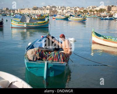 Un locale, Pescatore maltese in un colorato luzzu tradizionale barca da pesca nel porto di Marsaxlokk di Marsaxlokk, Malta. Foto Stock