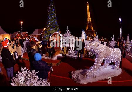 Parigi, Francia. 23 Dic, 2013. Le persone rappresentano per le foto in un'area decorata con alberi di Natale di fronte al illumina la Torre Eiffel a Parigi, Francia, Dic 23, 2013. Decorazioni natalizie e illuminazione sono stati istituiti presso le principali attrazioni turistiche di Parigi per la prossima stagione festiva. Credito: Chen Xiaowei/Xinhua/Alamy Live News Foto Stock