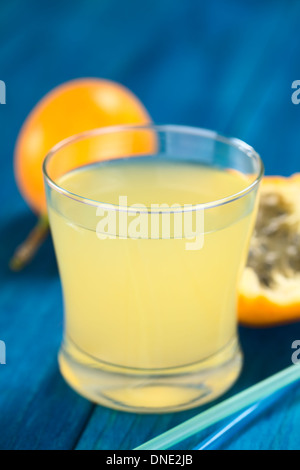 Succo di frutta fresco fatto di dolci granadilla o grenadia (lat. Passiflora ligularis) in vetro con cannucce potabile davanti Foto Stock