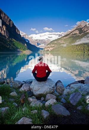 Metà maschio età meditando sulla roccia presso il Lago Louise, Alberta, Canada. Foto Stock
