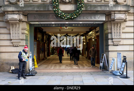 Manchester, Regno Unito. Il 24 dicembre 2013. Un grande problema venditore sorge fuori l'ingresso al Royal Exchange Arcade in Manchester. Lo spirito del Natale Manchester, Regno Unito 24 dicembre 2013 Credit: Giovanni friggitrice/Alamy Live News Foto Stock