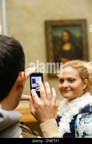L'uomo prendendo foto della donna di fronte Dipinto La Gioconda di Leonardo da Vinci, il museo del Louvre, Parigi, Francia Foto Stock