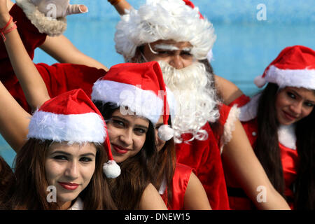 Bhopal in India. 24 dicembre, 2013. Le giovani ragazze vestite di Santa Claus costumi posano per una fotografia con "Santa Claus' durante la vigilia di Natale le celebrazioni a un parco acquatico a Bhopal in India, il 24 dicembre, 2013. Credito: Stringer/Xinhua/Alamy Live News Foto Stock