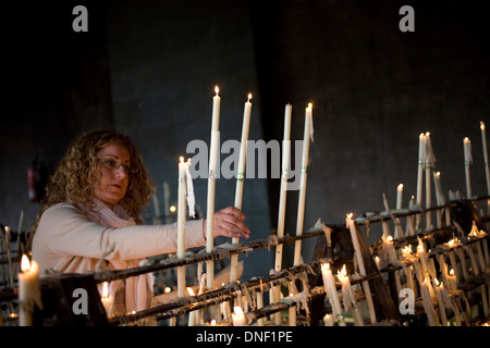 Una donna accende una candela nella camera votiva del Santuario di Nostra Signora del Rocio a El Rocio village, Andalusia, Spagna Foto Stock