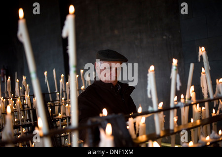 Un anziano uomo accende una candela nella camera votiva del Santuario di Nostra Signora del Rocio a El Rocio village, Andalusia, Spagna Foto Stock