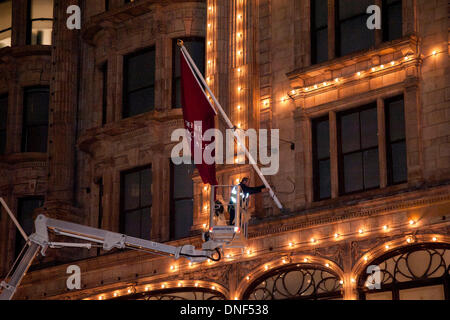 Londra, Regno Unito. Il 24 dicembre 2013. Un operaio mette su bandiere sul lato dell'edificio di Harrods. La vendita di Harrods si apre giovedì il 26 dicembre 2013. Credito: Pete Maclaine/Alamy Live News Foto Stock