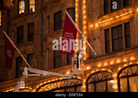 Londra, Regno Unito. Il 24 dicembre 2013. Un operaio mette su bandiere sul lato dell'edificio di Harrods. La vendita di Harrods si apre giovedì il 26 dicembre 2013. Credito: Pete Maclaine/Alamy Live News Foto Stock