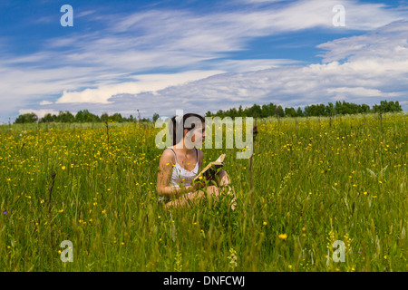 Giovane donna libro di lettura su un prato Foto Stock