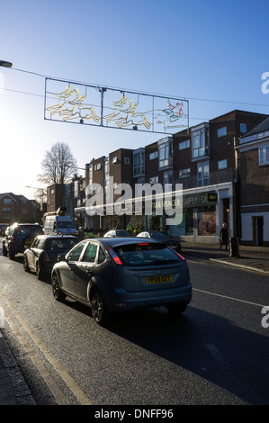 Una coda di traffico in Beaconsfield nuova città in bassa luce invernale; stagionale decorazioni natalizie attraversare la strada. Foto Stock