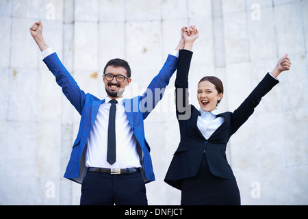 Happy businessman e imprenditrice con bracci sollevati guardando la fotocamera Foto Stock