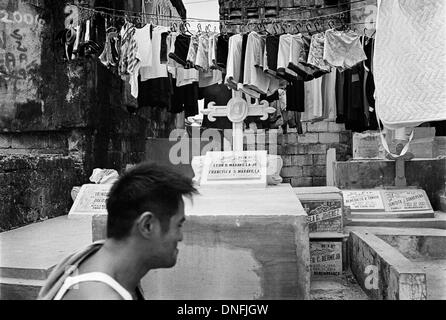 Manila, Filippine: uomo passa lungo tombe e stendibiancheria in Manila Nord cimitero Foto Stock