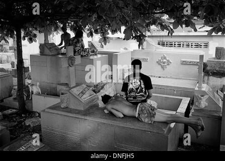 Manila, Filippine: persone in appoggio sulla sommità di tombe a Manila il cimitero del Nord Foto Stock