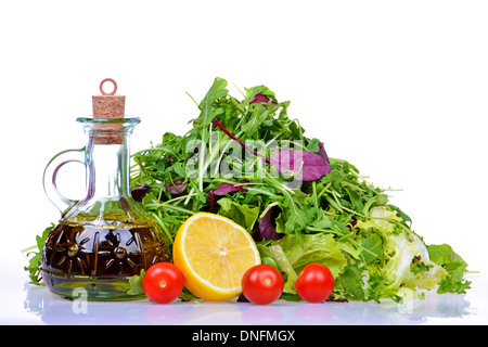 Mix di insalata con rucola, frisee, radicchio, lattuga e una bottiglia di olio di oliva, limone, pomodori Foto Stock