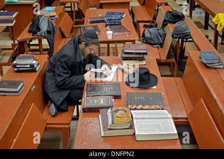 Un ebreo ortodosso studente studiare da soli in una grande sala ingombra in sede Lubavitch in Crown Heights, Brooklyn, NY Foto Stock