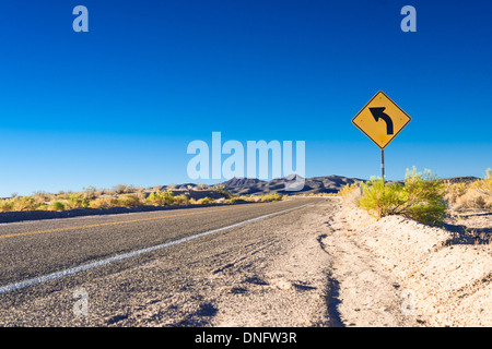 Strada nel deserto e girare il segno Foto Stock