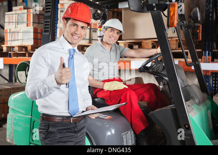 Supervisor gesticolando pollice fino a magazzino Foto Stock
