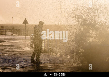 Aberystwyth, Wales, Regno Unito. Il 27 dicembre 2013. Gale force venti pastella la costa gallese e ad alta marea massiccia onde si infrangono sul fronte mare a Aberystwyth. Panna montata in schiuma dal vento che copre la spiaggia e il lungomare Sud come sta un uomo in silhouette contro il sole di setting, guardando la rottura a spruzzo sopra il mare di ringhiere. Credito: atgof.co/Alamy Live News Foto Stock