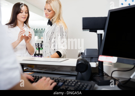 Addetto alle vendite ad assistere la donna in farmacia Foto Stock