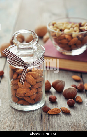 Mandorle in un barattolo di vetro con il dado mix su sfondo di legno Foto Stock