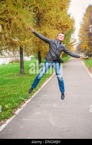 Giovane uomo bello il salto nel parco di autunno Foto Stock