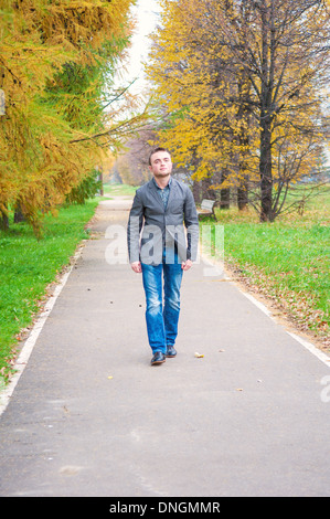 Giovane uomo bello camminare nel parco di autunno Foto Stock