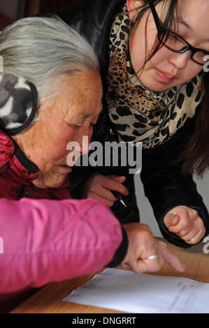 Wuyi, cinese della Provincia di Zhejiang. 29 Dic, 2013. Abitante Xu Sulan (L), 77, è aiutato a votare per un nuovo comitato di vigilanza su affari di villaggio in villaggio Houchen in Wuyi County, est della Cina di Provincia dello Zhejiang, Dic 28, 2013. Trentasei rappresentanti degli abitanti locali eletto il nuovo comitato di vigilanza, che aiuterebbe gli abitanti di un villaggio di supervisionare la gestione degli affari pubblici, come ad esempio le spese finanziarie e i progetti di costruzione. Il sistema è iniziata nel 2004. Credito: Tan Jin/Xinhua/Alamy Live News Foto Stock