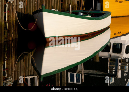 Primo piano della piccola barca bianca e di riflessione accanto a pier Foto Stock