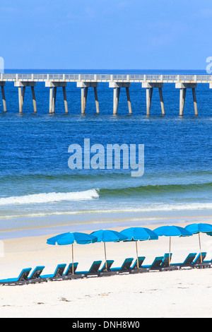 Sedie a sdraio e ombrelloni sulla spiaggia di sabbia con Pier Foto Stock