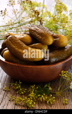 Cetrioli sottaceto in ciotola su una tavola di legno Foto Stock