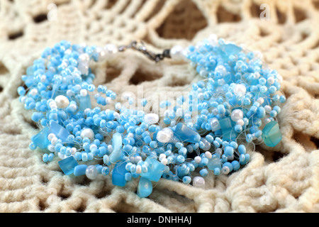 Bracciale fatti a mano di colore blu e bianco delle perline di vetro da India sullo sfondo a maglia Foto Stock