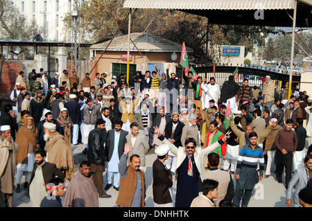 Sostenitori e attivisti del Tehreek-e-Insaf (PTI) chant slogan contro il prezzo escursionismo e elettricità alleggerimento del carico durante la manifestazione di protesta a Wapda House di Peshawar press club il Lunedi, 30 dicembre 2013. Foto Stock