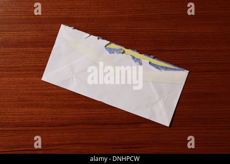 Una posta di aria della busta di affrancatura postale leggermente usurato e strappato su una superficie di legno. Foto Stock
