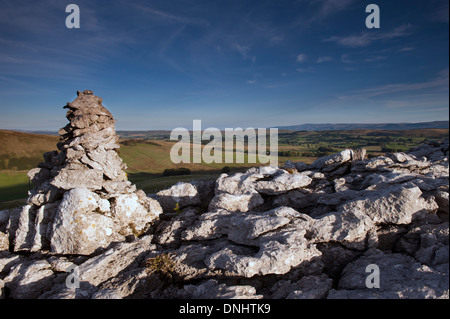 Calcare Cairn cattura primi raggi di sole sulla estremità cadde nuvole, una zona di pavimentazione di pietra calcarea vicino Ravenstonedale, Cumbria. Foto Stock