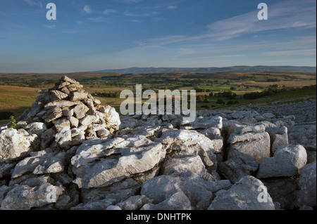 Calcare Cairn cattura primi raggi di sole sulla estremità cadde nuvole, una zona di pavimentazione di pietra calcarea vicino Ravenstonedale, Cumbria. Foto Stock