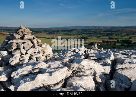 Calcare Cairn cattura primi raggi di sole sulla estremità cadde nuvole, una zona di pavimentazione di pietra calcarea vicino Ravenstonedale, Cumbria. Foto Stock