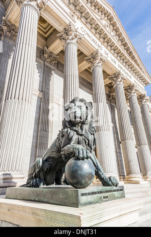 Vista del leone di bronzo statua a pillared entrata dell'iconico Congreso de los Diputados (Congresso dei Deputati), Plaza de las Cortes, Madrid, Spagna Foto Stock