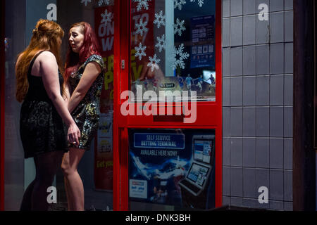 Cardiff, Regno Unito. Il 1 gennaio 2014. Due donne hanno una conversazione alla porta di un negozio di scommesse. Le persone si sono riunite nella capitale gallese per vedere all'inizio del 2014. Credito: Polly Thomas / Alamy Live News Foto Stock