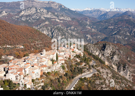 VISTA AEREA. Borgo medievale arroccato con le Alpi del Mercantour all'orizzonte. Bouyon, Alpes-Maritimes, entroterra della costa azzurra, Francia. Foto Stock