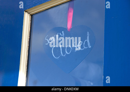 Siamo spiacenti ma chiuso sul segno a forma di cuore dietro blackboard shop finestrino di portiera Foto Stock