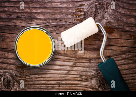 Piccolo rullo di vernice e colore barattolo di latta su uno sfondo di legno vecchio. Ristrutturazione e rinnovamento del concetto. Foto Stock