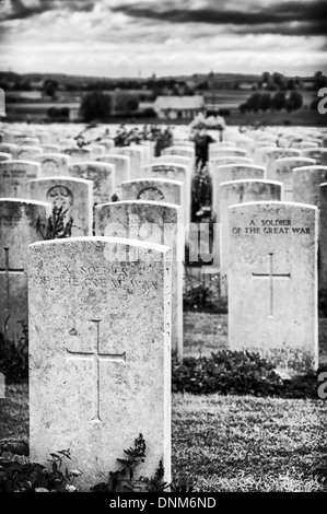 Lapidi di soldati in Tyne Cot cimitero di guerra con i campi di battaglia Paschendaele in background Foto Stock