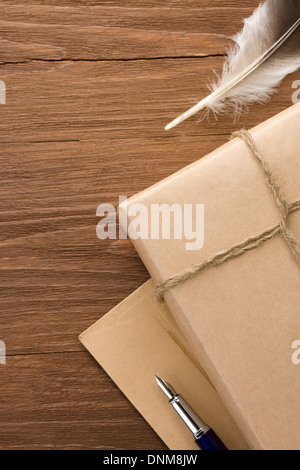 Pacco avvolto con carta marrone legato con la fune su uno sfondo di legno Foto Stock