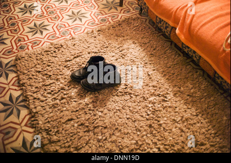 Stivali vecchi su rug,pavimento piastrellato Foto Stock