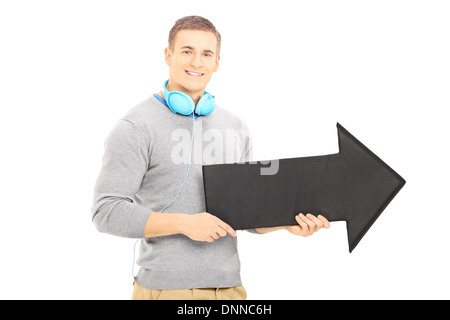 Ragazzo sorridente con cuffie tenendo un grande nero freccia che punta a destra Foto Stock