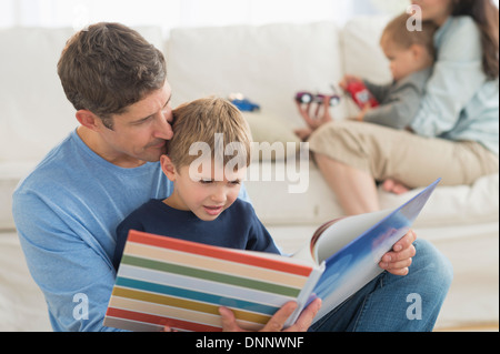 I genitori con bambini (12-17 mesi, 6-7) in casa, la lettura di padre in figlio Foto Stock