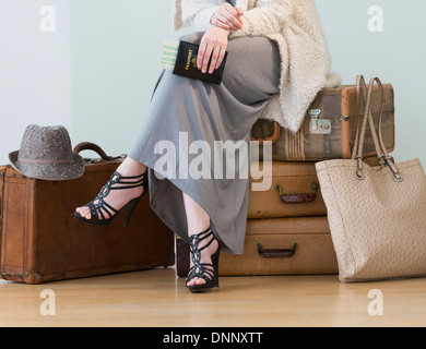 Donna seduta sulla pila di valige vintage Foto Stock