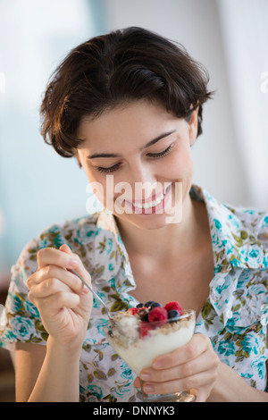 Donna di mangiare lo yogurt con frutta Foto Stock