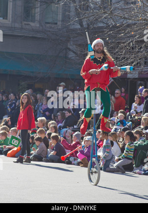 Asheville, North Carolina, Stati Uniti d'America - 17 Novembre 2012: un colorato giocoliere vestito come un elfo cavalca un monociclo intrattiene i bambini e Foto Stock